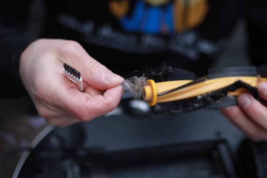 Haare werden aus der Bürste des Yeedi Vac 2 Pro per Hand entfernt 